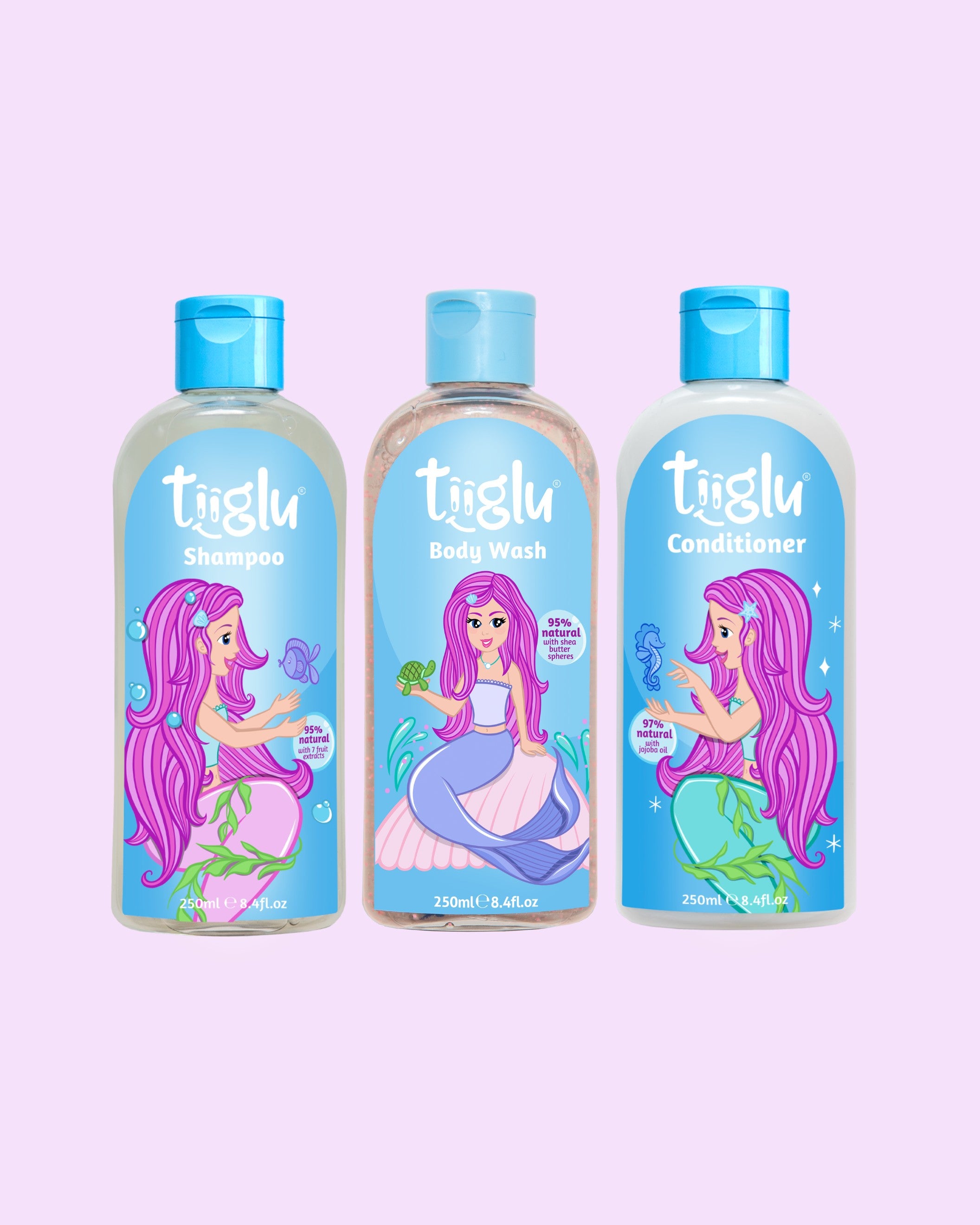 Tiiglu® Kids Mermaid Dazzle Set with Shampoo (95% natural), Body Wash (95% natural), and Conditioner (97% natural), each 250ml, featuring a pink-haired mermaid on light blue labels, jumping jelly beans-scented, on a light pink background.