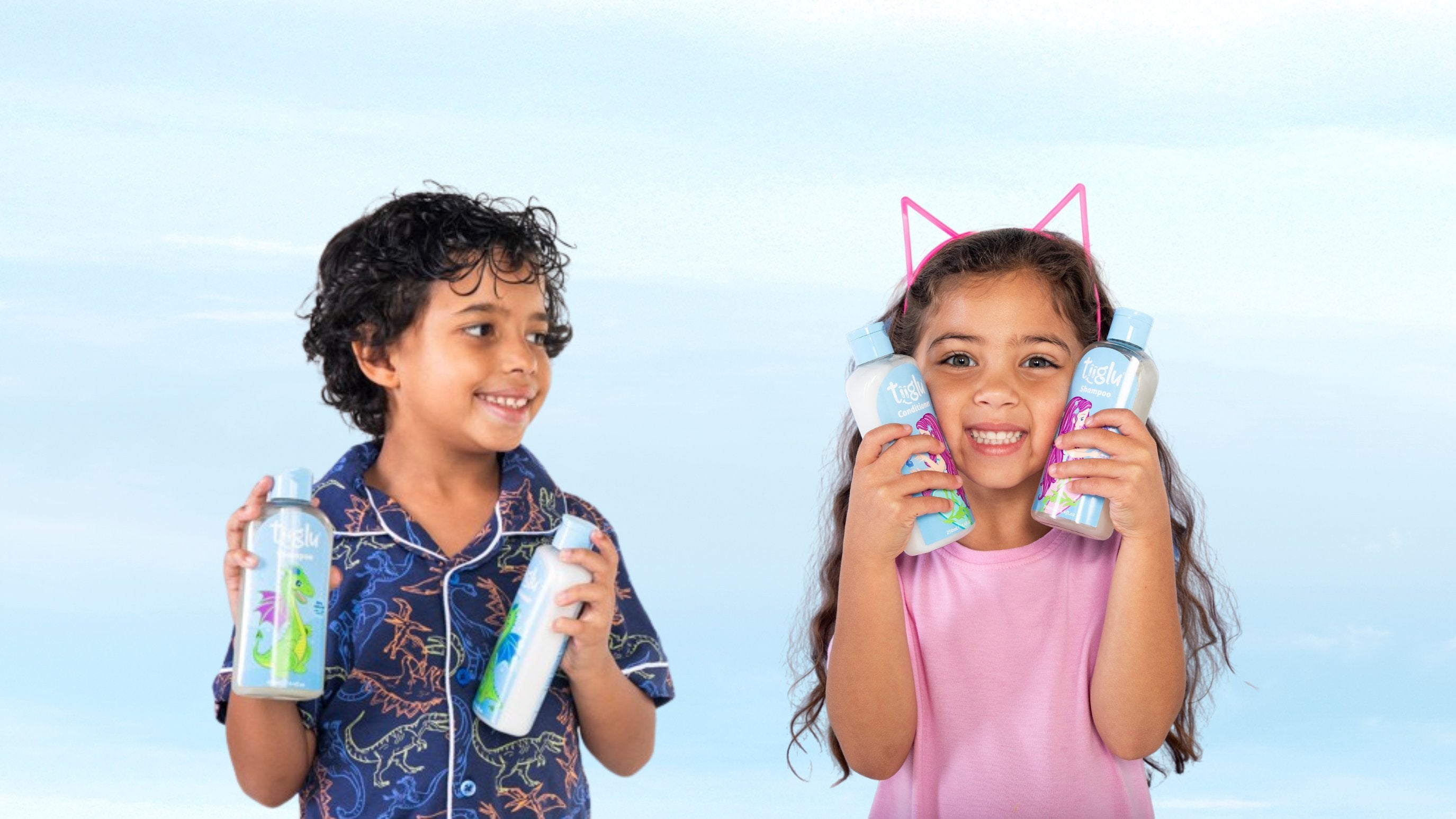 A boy in dragon pajamas and a girl with cat ears hold Tiiglu® body wash bottles with dragon and mermaid designs. This Sets section banner promotes kids’ body and hair care sets with fruity fresh washes.