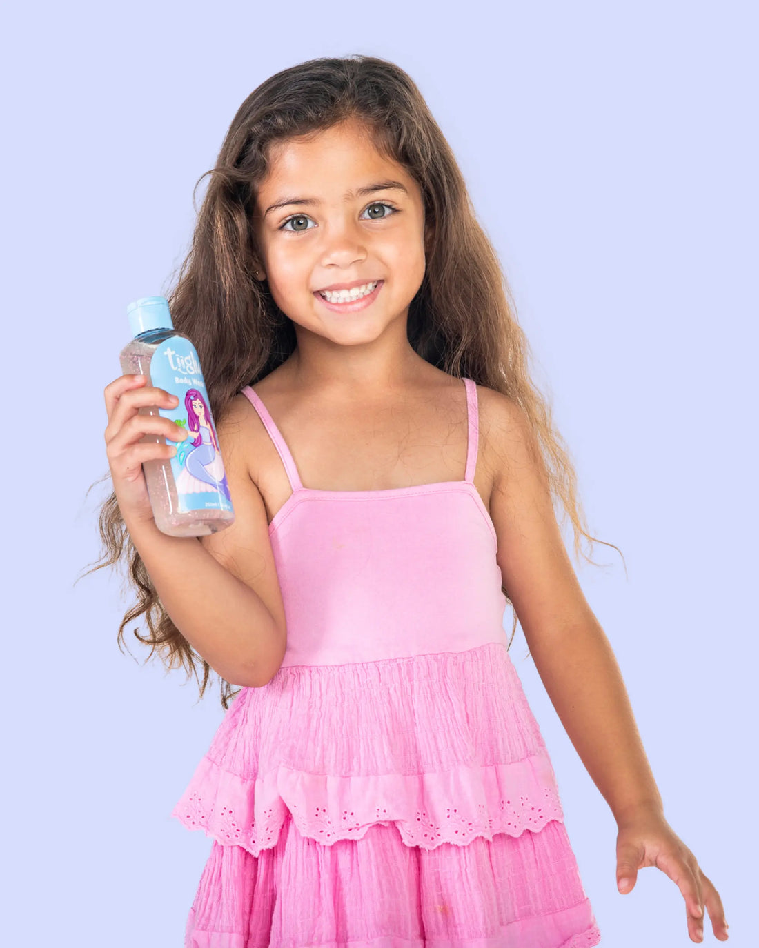 A girl in a pink dress holding a Tiiglu® Kids Mermaid Body Wash bottle (250ml) with a pink-haired mermaid on a light blue label, &
