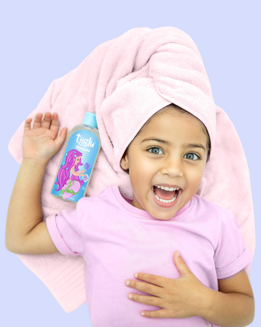 A girl in a pink shirt with a pink towel around her head, lying next to a Tiiglu® Kids Mermaid Shampoo bottle (250ml) with a pink-haired mermaid on a light blue label, &